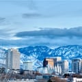 This image shows the downtown skyline of Salt Lake City, Utah, with the snowy Wasatch Mountains in the background.