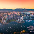 The image appears to show an aerial view of Vancouver, British Columbia, Canada, looking south over False Creek toward the downtown peninsula and the North Shore Mountains.