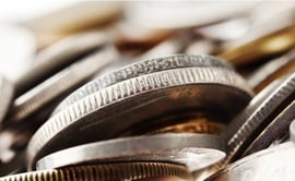 The image shows a close-up macro shot of various metal coins piled and stacked together.
