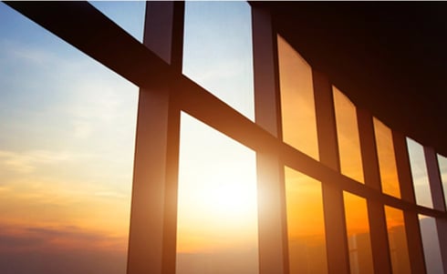 This image appears to show a panoramic glass window inside a modern medical building during a bright sunset or sunrise.